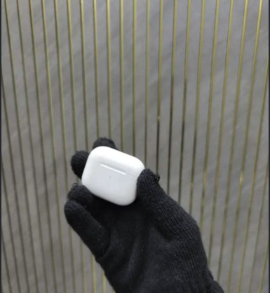 AirPods case held up in a gloved hand
