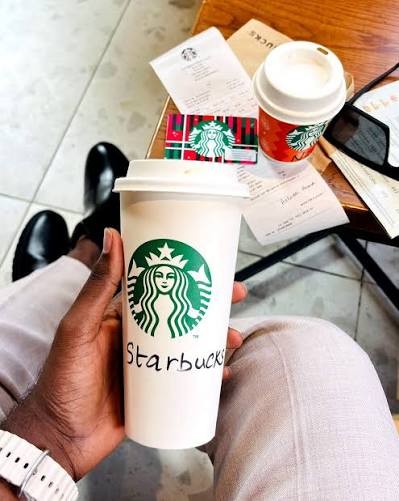 A Starbucks cup held in a cafe
